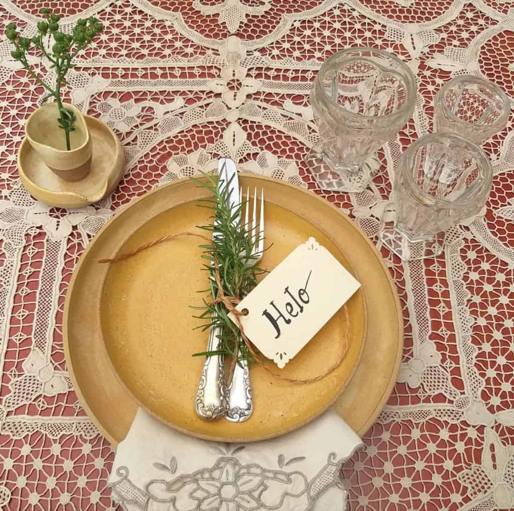 Foto feita de cima mostra lugar na mesa posta de Natal com pratos em tom de bege.